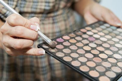 Midsection of woman holding make-up brush and palette