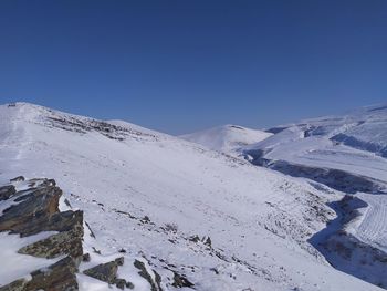 Scenic view of snowcapped mountains against clear blue sky