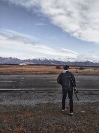 Rear view of man standing on field against sky