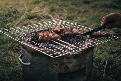 Hand holding meat on barbecue grill