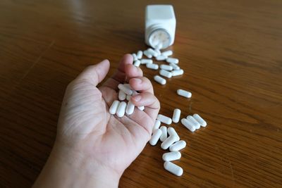 Cropped hand holding capsules at table