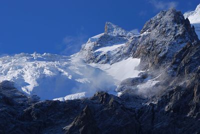 Snow covered mountain against blue sky