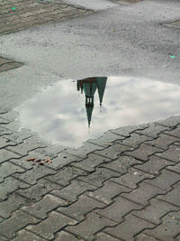 Reflection of man in puddle on street