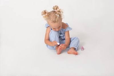 Little girl sitting on the floor painting her toenails