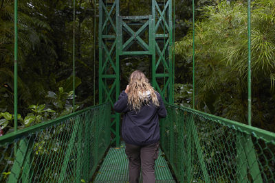 Rear view of woman walking on footbridge