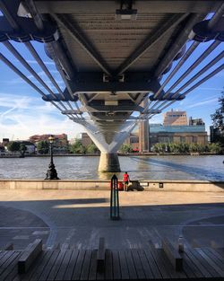 People on bridge over river against sky in city