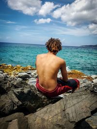 Rear view of shirtless man looking at sea against sky