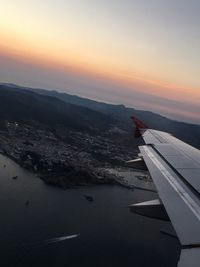 Airplane flying over sea against sky during sunset