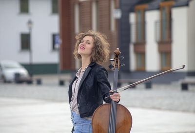 Portrait of smiling woman holding violin on street