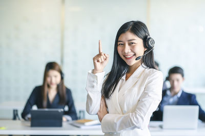 Portrait of smiling young woman using smart phone on table