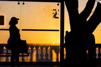 Silhouette people standing against orange sky