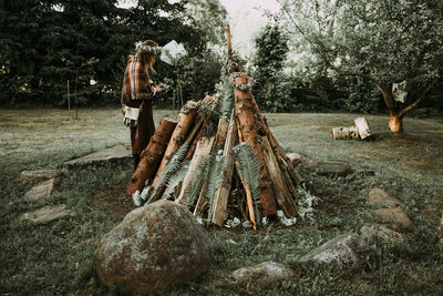 Woman standing on field by logs