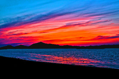 Scenic view of sea against dramatic sky during sunset