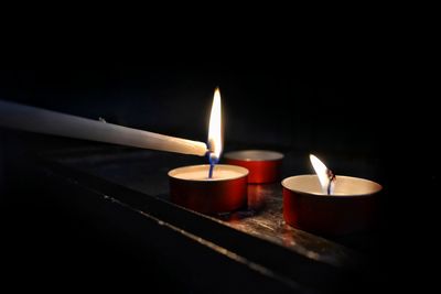 Close-up of illuminated tea light candles in darkroom