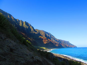 Scenic view of sea and mountains against clear blue sky