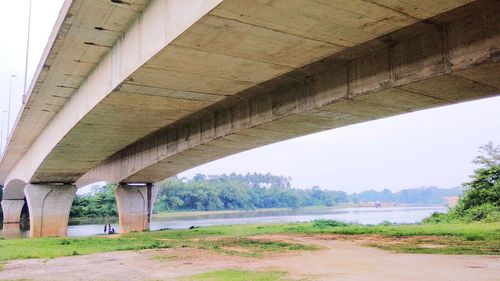 Bridge over road by river against sky