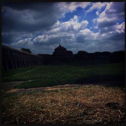 View of field against cloudy sky