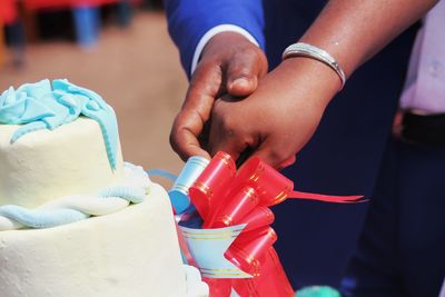 Close-up of couple cutting cake