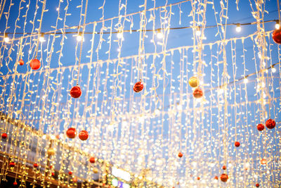 Low angle view of illuminated lanterns hanging against blue sky