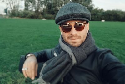 Mid adult man wearing sunglasses standing on grassy field at park