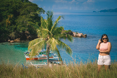Rear view of woman sitting on beach against sky