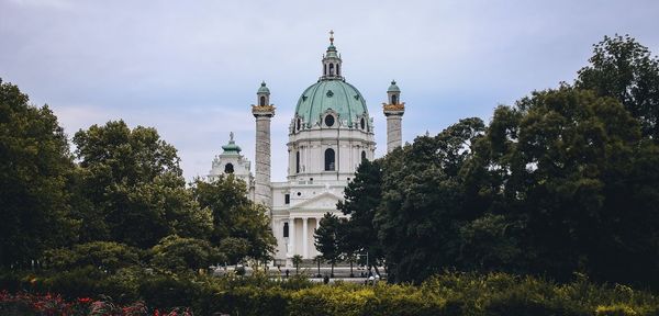 View of cathedral and trees against cloudy sky