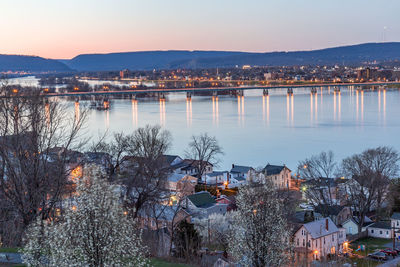 High angle view of river by buildings in city at sunset