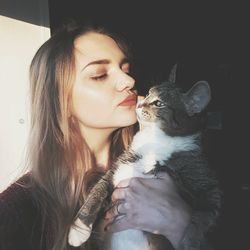 Young woman kissing her cat