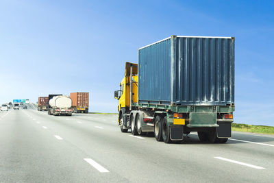 Vehicles on road against blue sky