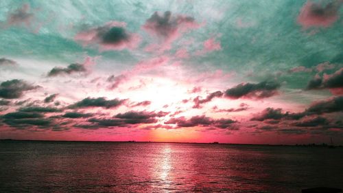 Scenic view of sea against cloudy sky at sunset