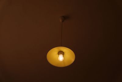 Low angle view of illuminated light bulb hanging from ceiling