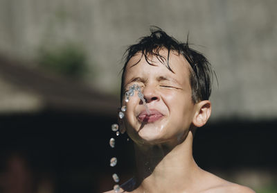 Close-up of boy spilling water outdoors