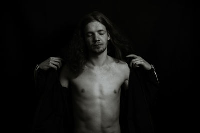 Shirtless young man against black background