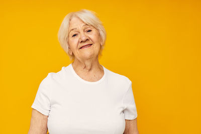 Portrait of young woman against yellow background