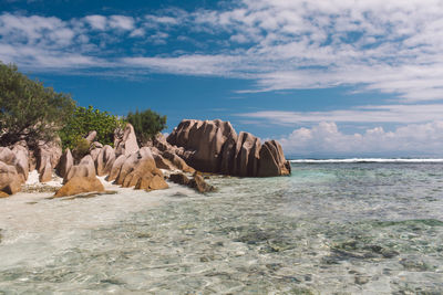 Rock formations on beach against sky