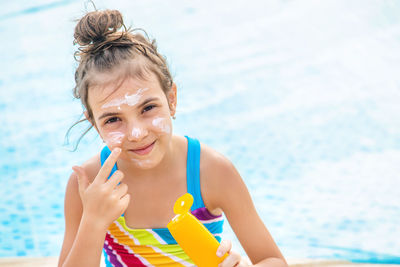 Portrait of smiling girl applying suntan lotion on face