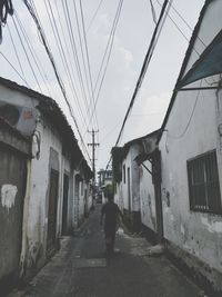 Rear view of man walking on street amidst buildings in city