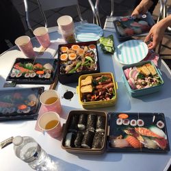 High angle view of hands holding sushi container at table in restaurant