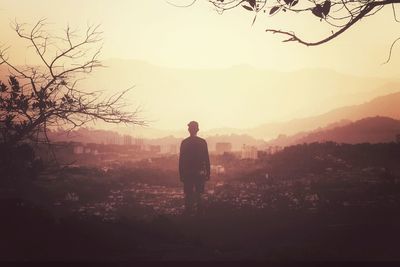 Rear view of silhouette man standing on mountain against sky