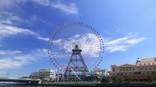 Low angle view of ferris wheel against cloudy sky