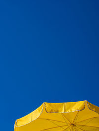 Low angle view of yellow tent against clear blue sky