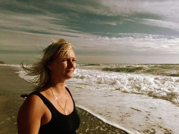 Woman standing on shore at beach against sky