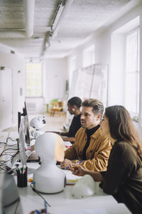 Phd students discussing over computer in innovation lab