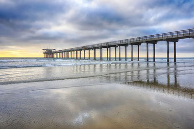 Pier over sea against sky during sunset