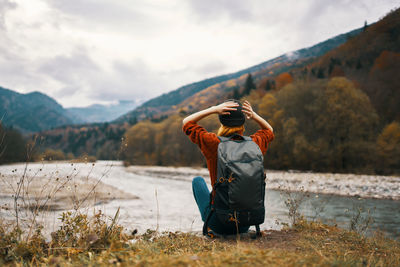 Rear view of man standing on mountain against sky