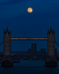 Full moon over bridge against blue sky at dusk