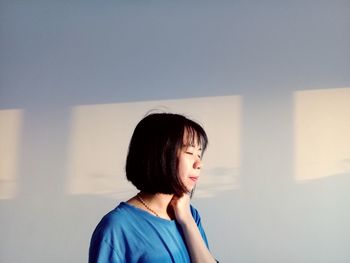 Portrait of a young woman looking away against wall