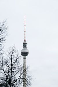 Low angle view of communications tower in city against sky