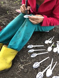 Low section of woman writing on spoon at field