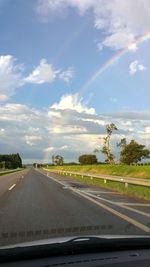 Road by trees against sky